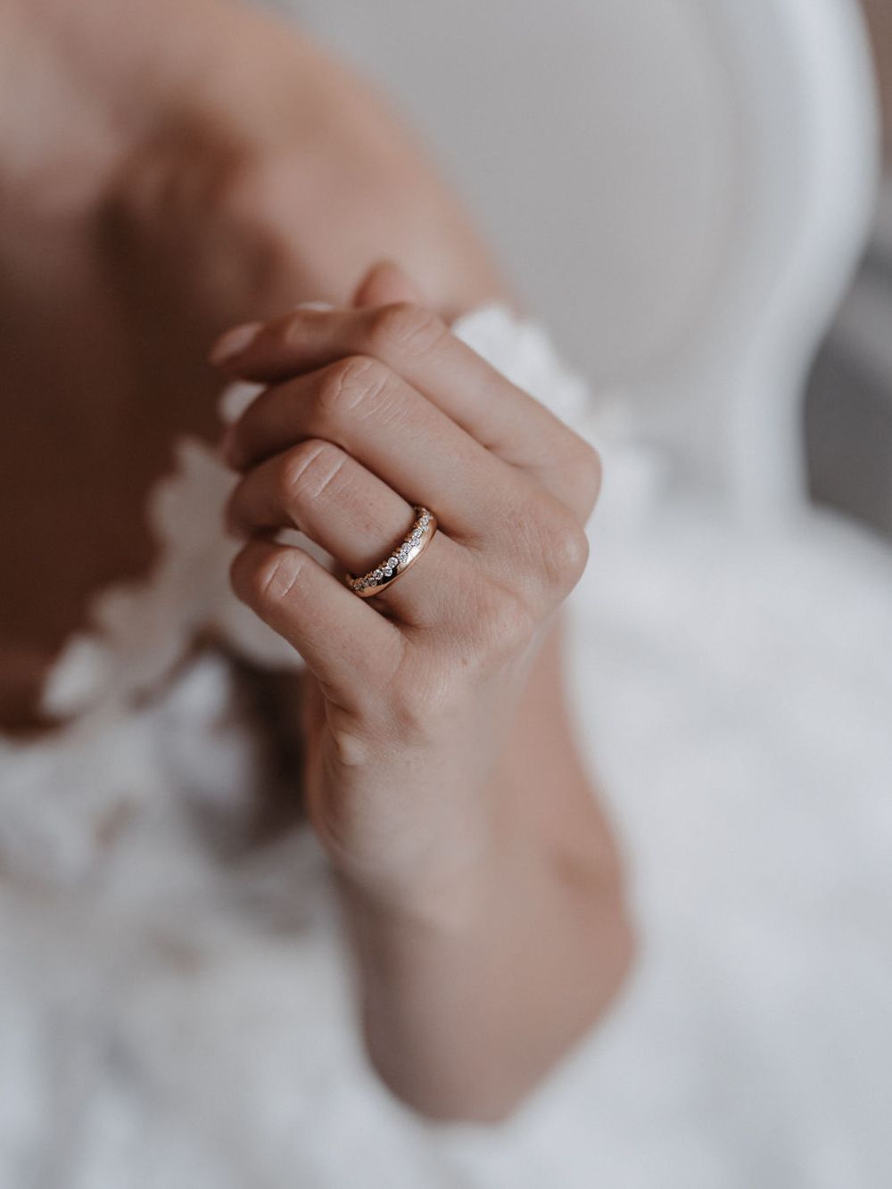 Hand der Braut mit Trauring am Spitzenkleid