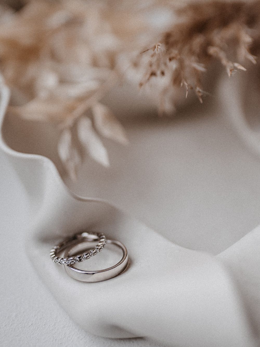 Ringe auf hellem Stoff zwischen Trockenblumen