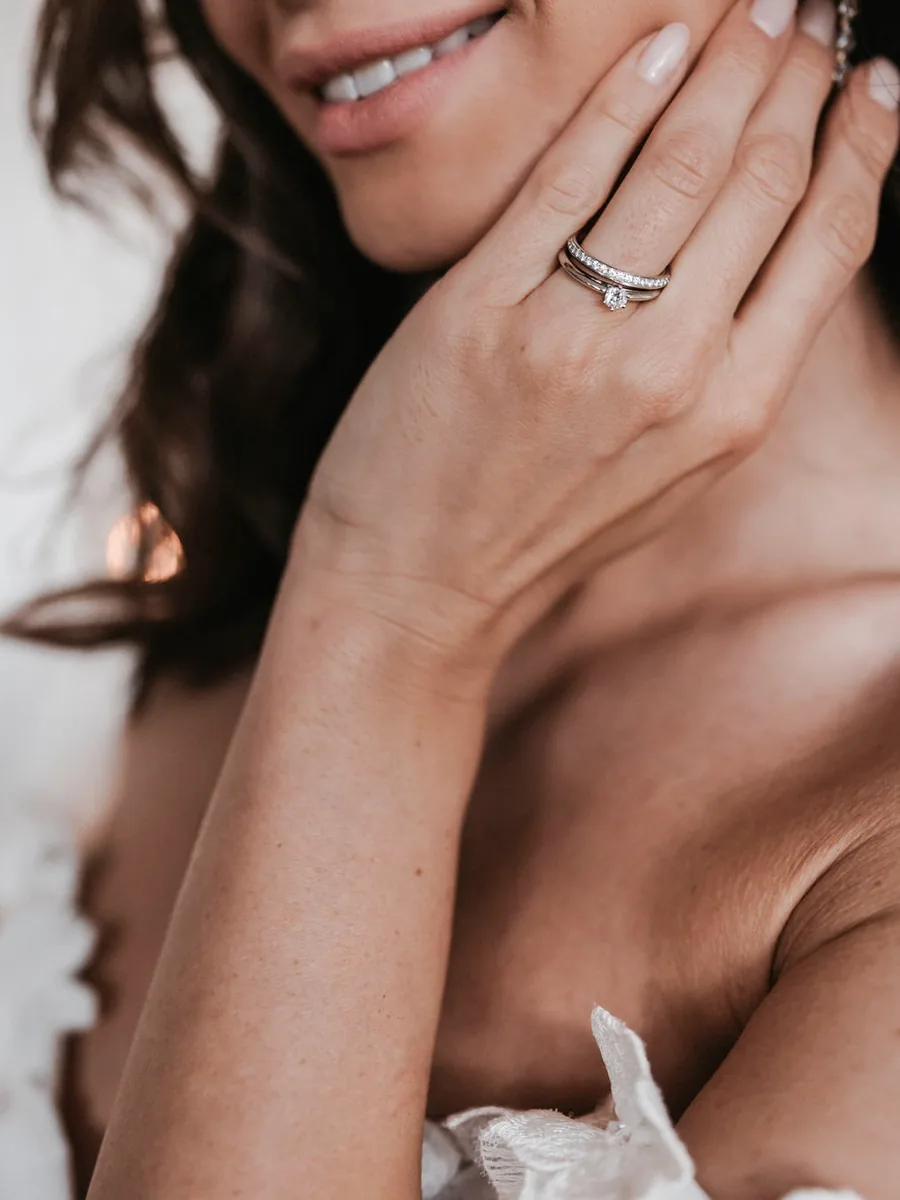 Braut mit Verlobungsring und schmalem Memoire-Ring in Weißgold, die Hand am Gesicht — Verlobungsringe bei Juwelier Otto Parr in Gießen
