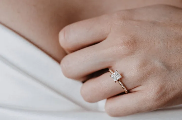 Hand mit einem Verlobungsring mit Solitär über dem weißen Brautkleid — Juwelier Otto Parr in Gießen