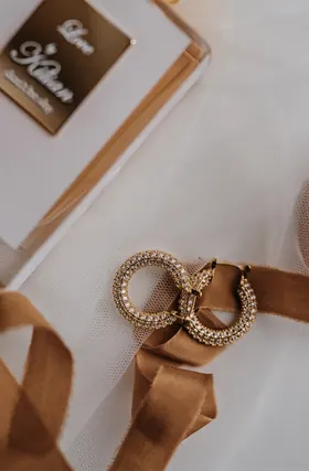 Zwei goldene Ringe mit gedrehter Oberfläche auf goldfarbenem Satinband