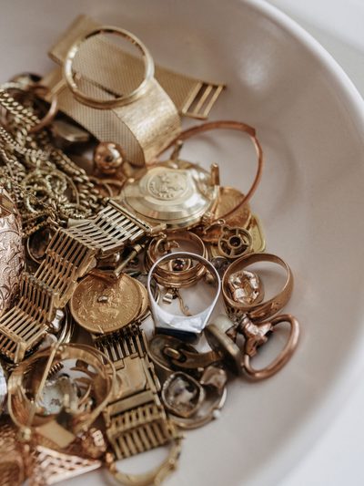 Weiße Schale gefüllt mit altem Goldschmuck, Ketten und Uhrengehäusen