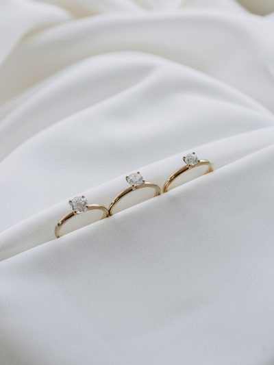 Drei Solitärringe aus Gelbgold nebeneinander auf weißem Satin, die Steine werden von links nach rechts größer