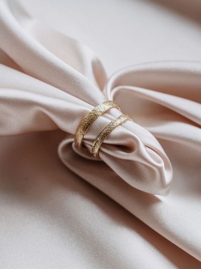 Zwei Trauringe aus Gelbgold auf einer Schleife aus Satin