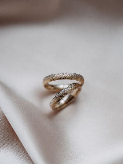 Zwei Trauringe mit feinem Brillantbesatz auf champagnerfarbenem Satin